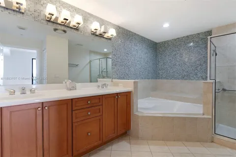 a bathroom with a tub a sink double vanity and a mirror