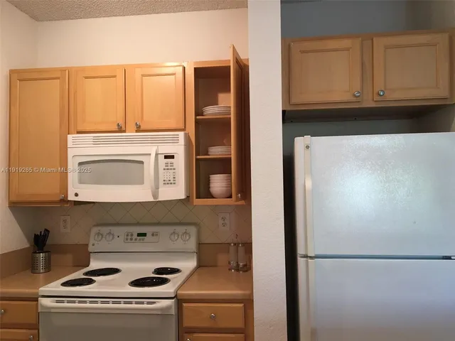 a kitchen with granite countertop a refrigerator and a stove top oven