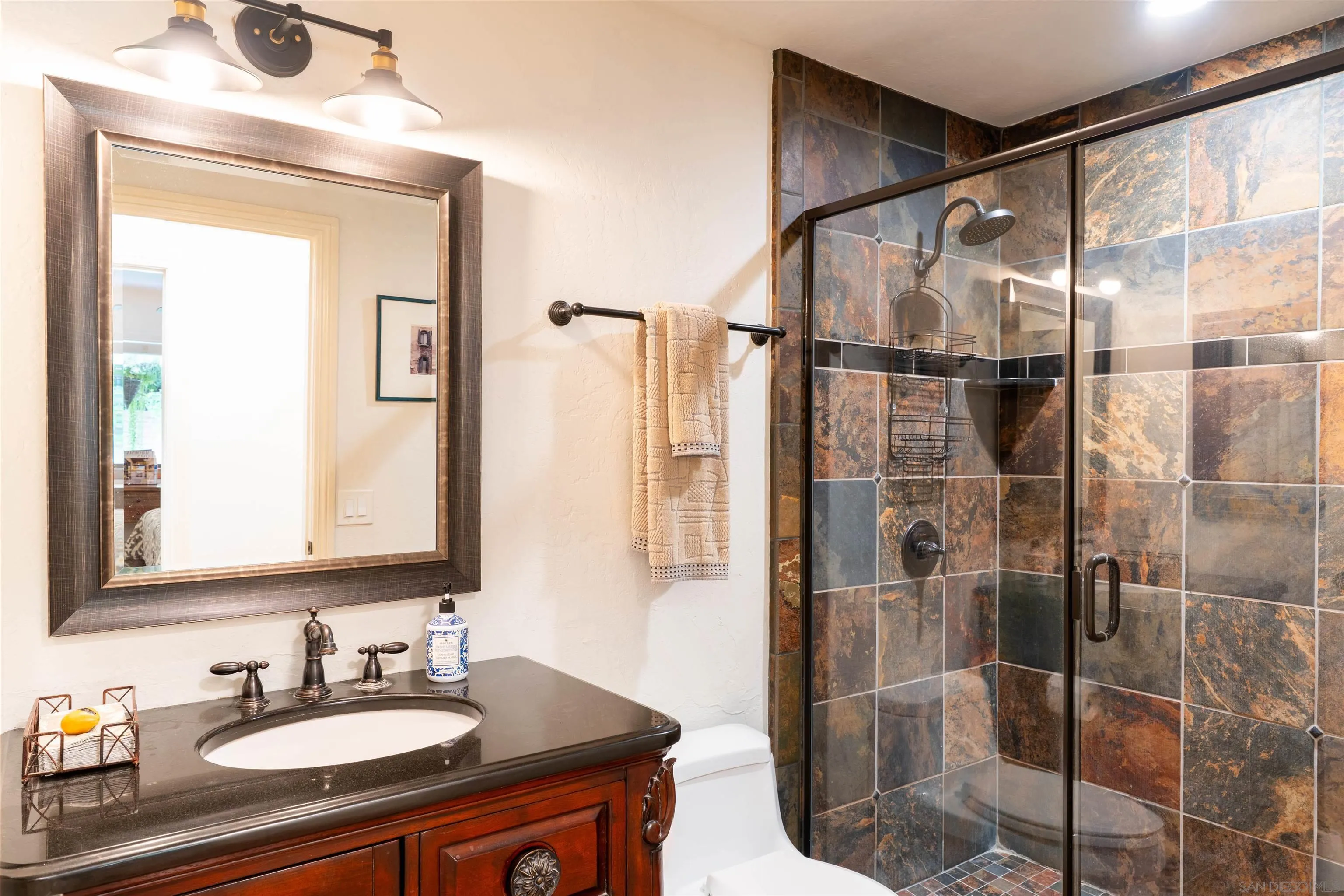 1036 Capra Way Fallbrook, CA 92028 - Photo 23 of 51 a bathroom with a shower sink and mirror
