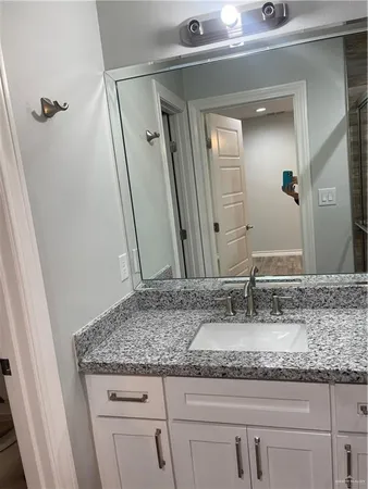 a bathroom with a granite countertop sink and a mirror