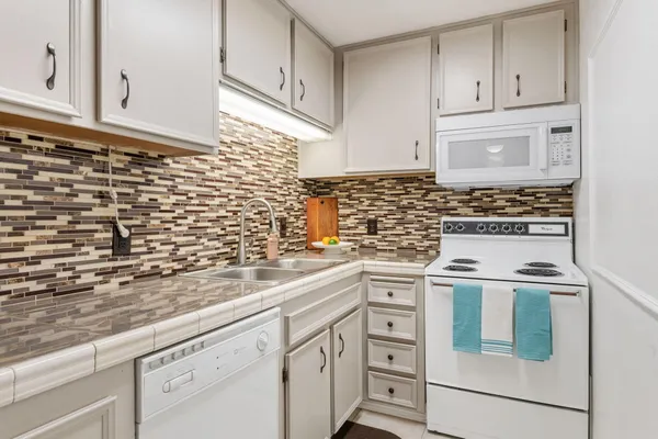 a kitchen with granite countertop white cabinets and white appliances