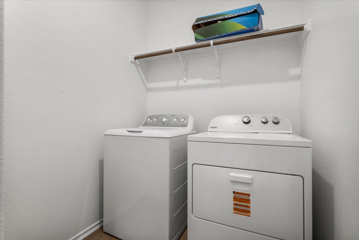 448 Perfect World Loop Jarrell, TX 76537 - Photo 22 of 40 An organized laundry room featuring a washer, dryer, and convenient overhead shelving for storage.
