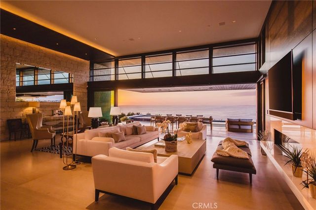 a living room with couches a flat screen tv and kitchen view