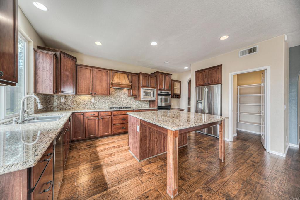 32215 Vía Bejarano Temecula, CA 92592 - Photo 7 of 42 a kitchen with kitchen island granite countertop wooden cabinets a sink and a stove