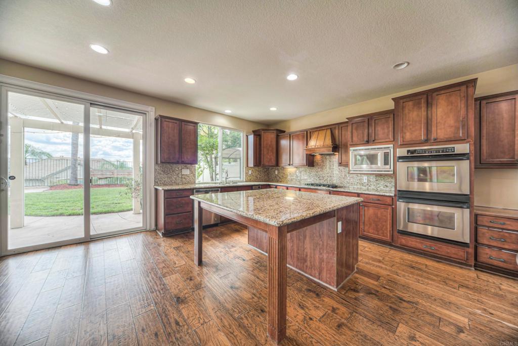 32215 Vía Bejarano Temecula, CA 92592 - Photo 8 of 42 a kitchen with kitchen island granite countertop wooden floors and wide window