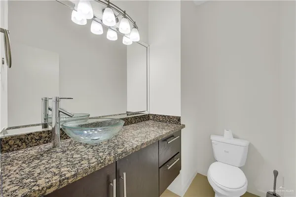 a bathroom with a granite countertop sink a toilet and a mirror