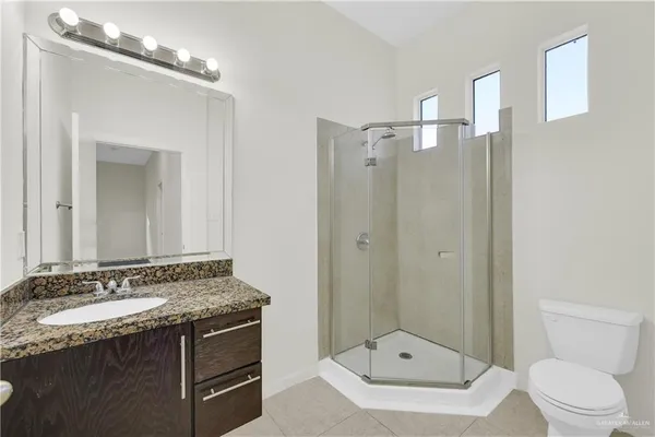 a bathroom with a granite countertop sink a mirror and a toilet