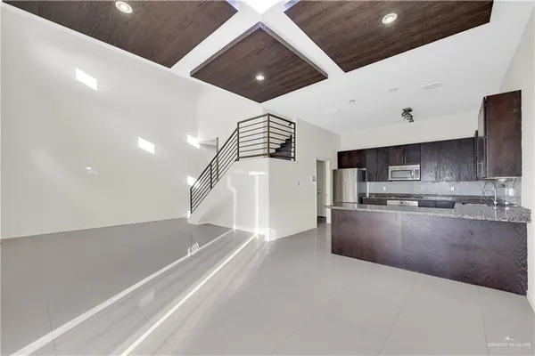 a kitchen with stainless steel appliances kitchen island granite countertop a refrigerator and a sink