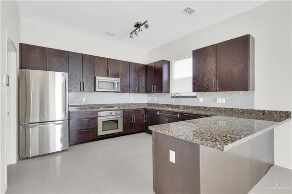 a kitchen with stainless steel appliances granite countertop a refrigerator a stove a sink and a microwave