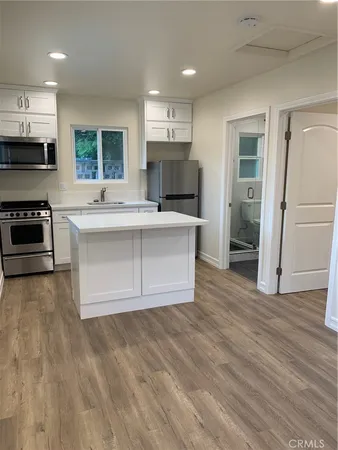 a view of kitchen with granite countertop a stove top oven a sink dishwasher and a refrigerator with wooden floor