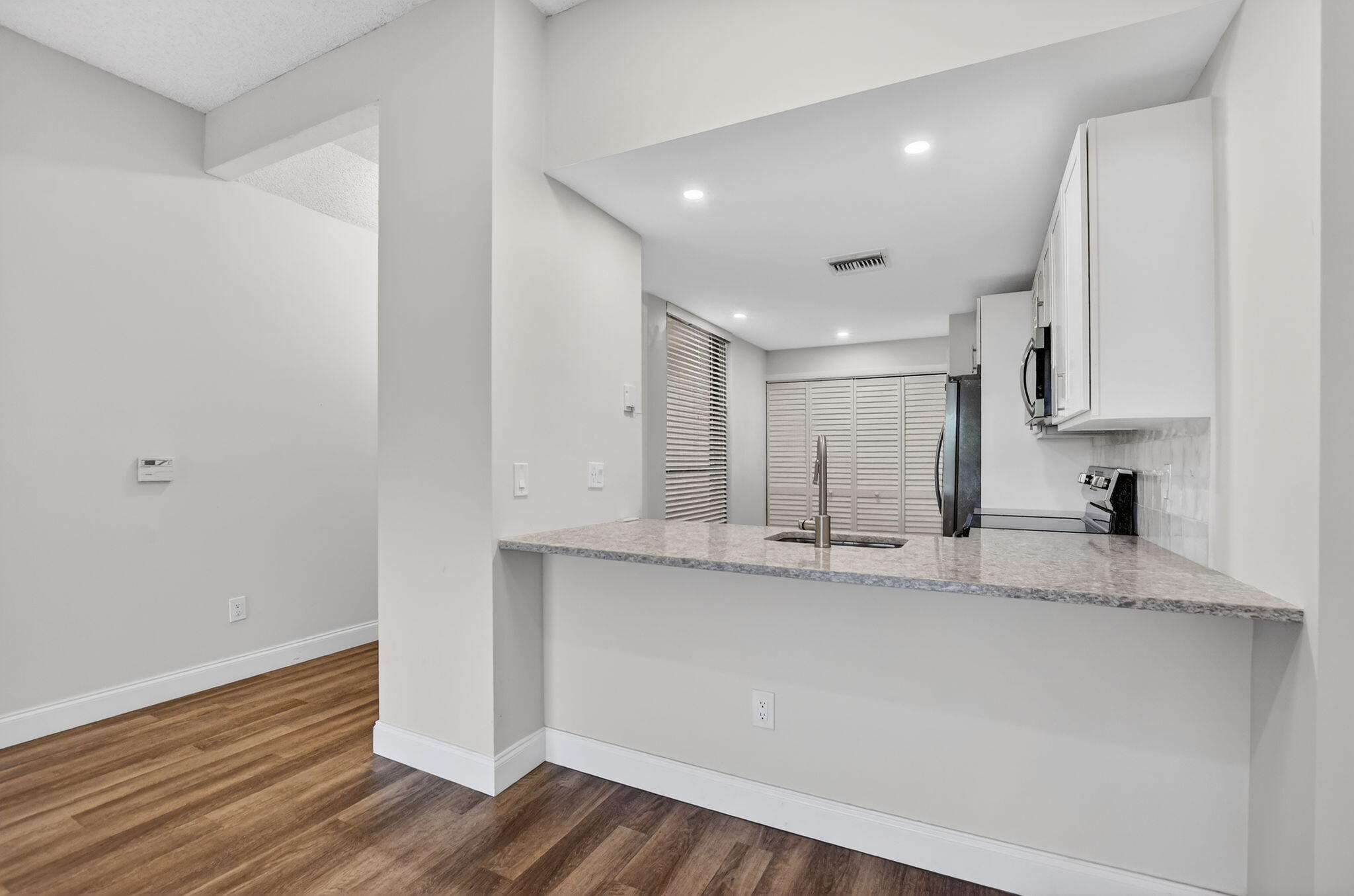7472 La Paz Boulevard, Unit 304 Boca Raton, FL 33433 - Photo 9 of 36 a view of a kitchen with granite countertop cabinets and wooden floor