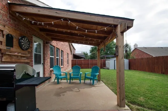 a view of a backyard with table and chairs potted plants and wooden fence