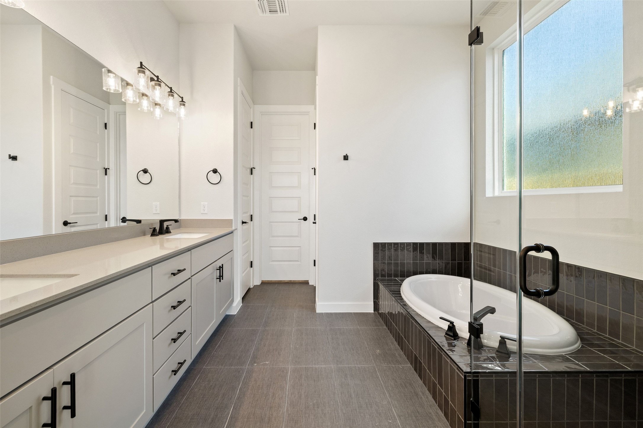 16309 Smithers Road Manor, TX 78653 - Photo 22 of 40 a spacious bathroom with a double vanity sink a mirror a bathtub and shower