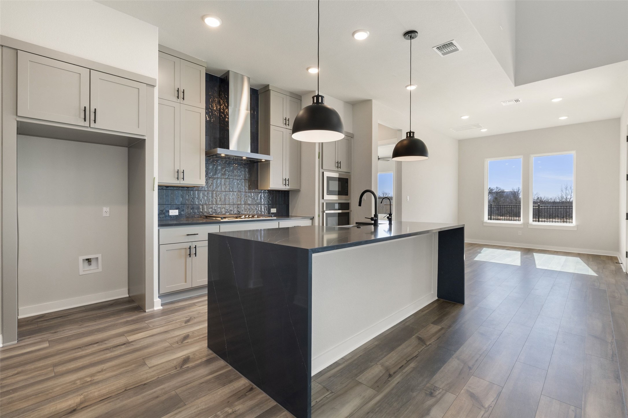 16309 Smithers Road Manor, TX 78653 - Photo 9 of 40 a large kitchen with stainless steel appliances kitchen island granite countertop a stove a refrigerator a sink and a microwave