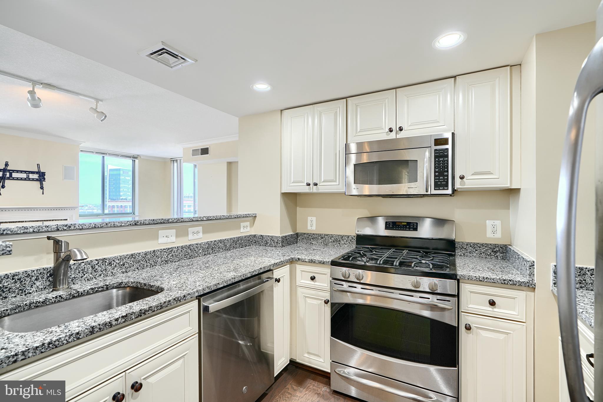 414 Water Street, Unit 1513 Baltimore, MD 21202 - Photo 11 of 43 a kitchen with granite countertop a sink stove and microwave