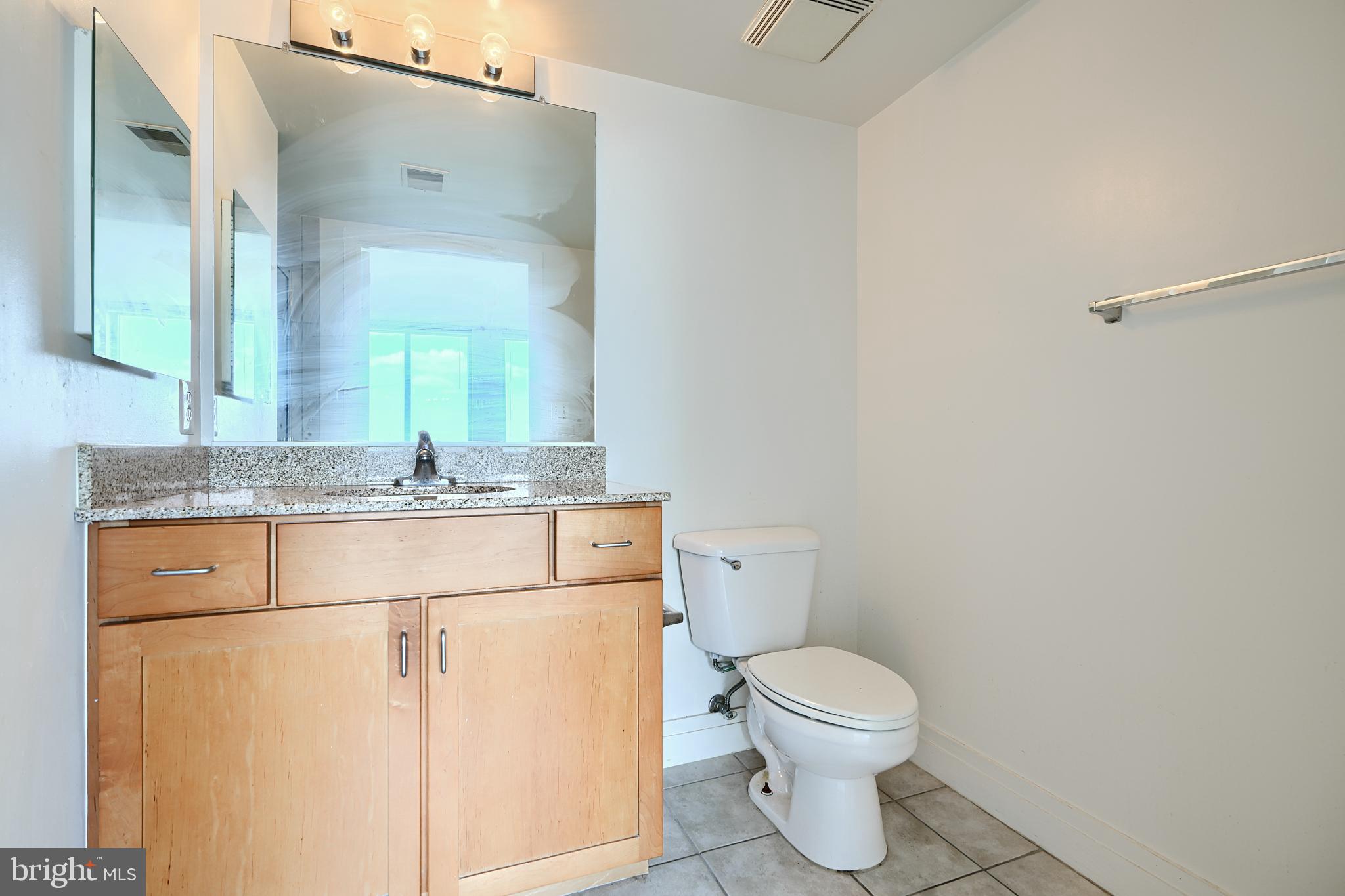 414 Water Street, Unit 1513 Baltimore, MD 21202 - Photo 31 of 43 a bathroom with a granite countertop toilet sink and mirror