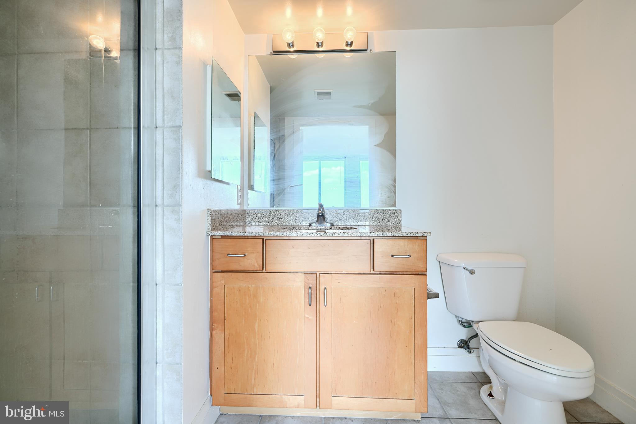 414 Water Street, Unit 1513 Baltimore, MD 21202 - Photo 32 of 43 a bathroom with a granite countertop sink mirror and toilet