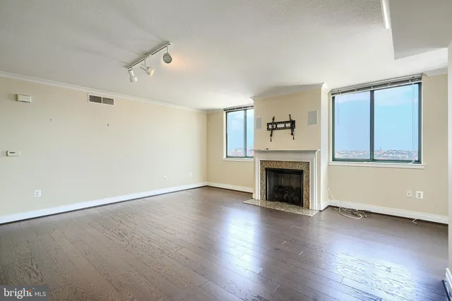 an empty room with wooden floor fireplace and windows