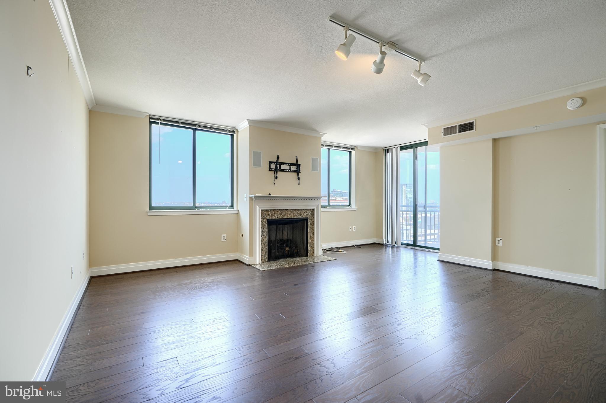 414 Water Street, Unit 1513 Baltimore, MD 21202 - Photo 5 of 43 an empty room with wooden floor fireplace and windows