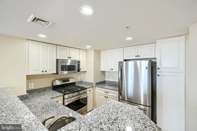 a kitchen with granite countertop a sink stove and microwave