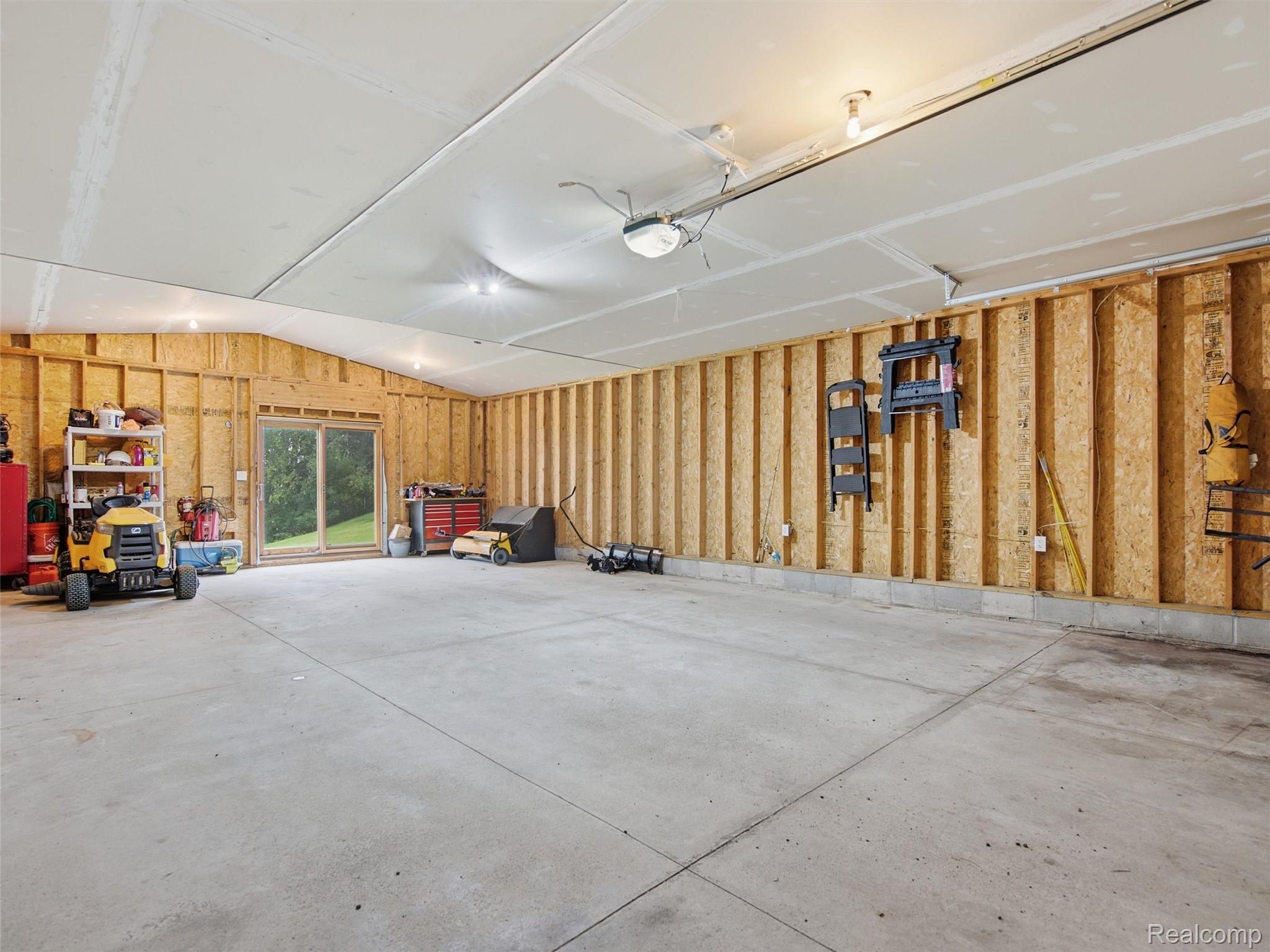 5003 Mason Road Howell, MI 48843 - Photo 44 of 59 Spacious garage area featuring a concrete floor, exposed wood stud walls, and overhead lighting