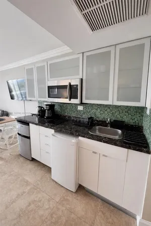 a living room with furniture a flat screen tv and a refrigerator