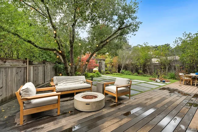 a view of a patio with a dining table and chairs with wooden floor and fence
