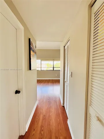 a view of an empty room with window and wooden floor