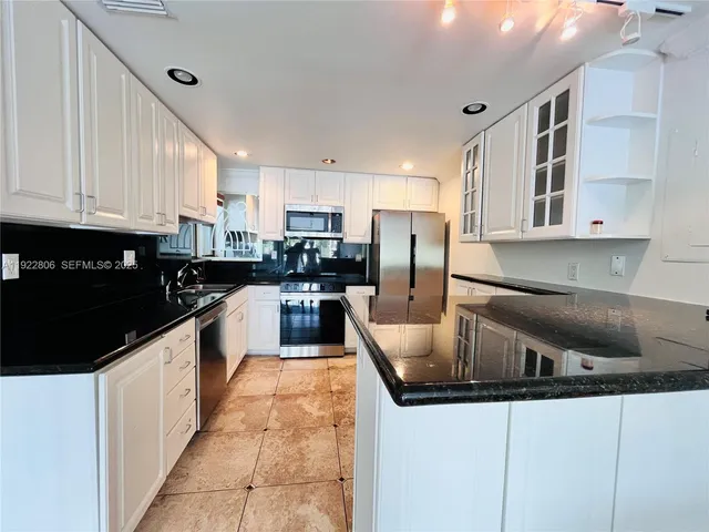 a kitchen with stainless steel appliances granite countertop a sink a stove and a refrigerator