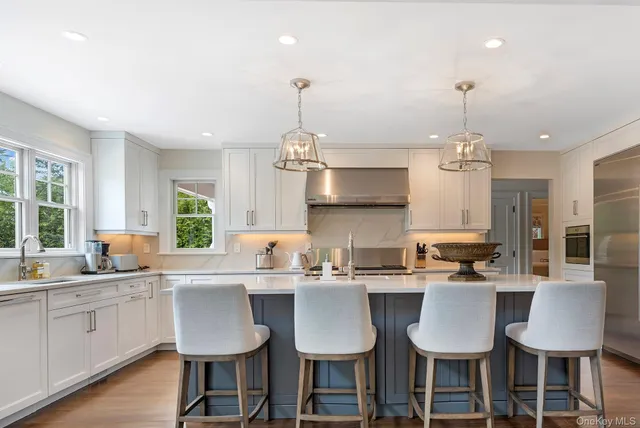 a very nice looking kitchen with granite countertop a sink large window and chairs