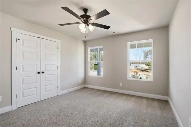 an empty room with windows and fan