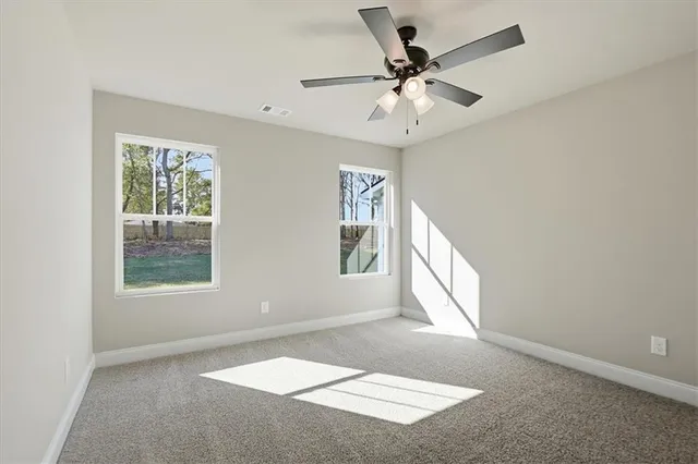 an empty room with windows and fan