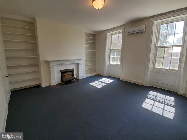 an empty room with windows and fireplace