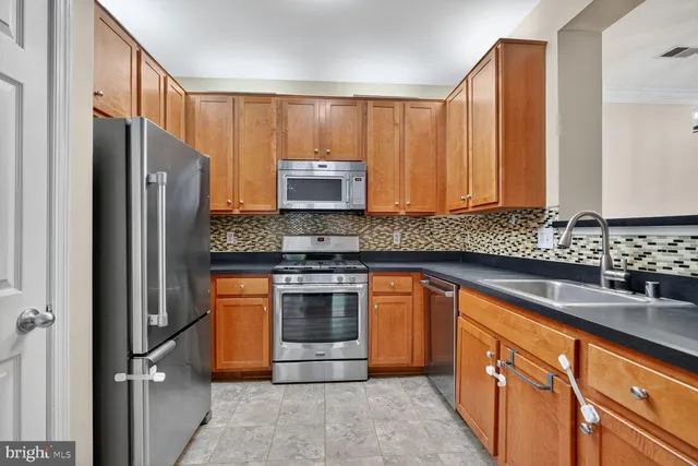 a kitchen with granite countertop wooden floors stainless steel appliances and sink