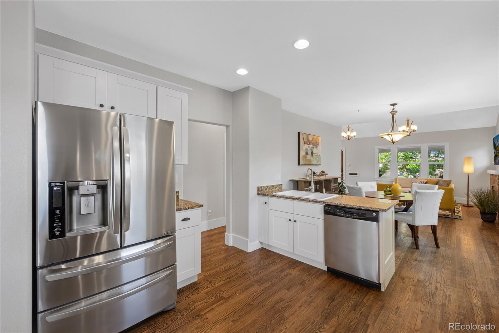 2829 Ash Street Denver, CO 80207 - Photo 14 of 40 a kitchen with stainless steel appliances a refrigerator a sink dishwasher a stove and white cabinets with wooden floor