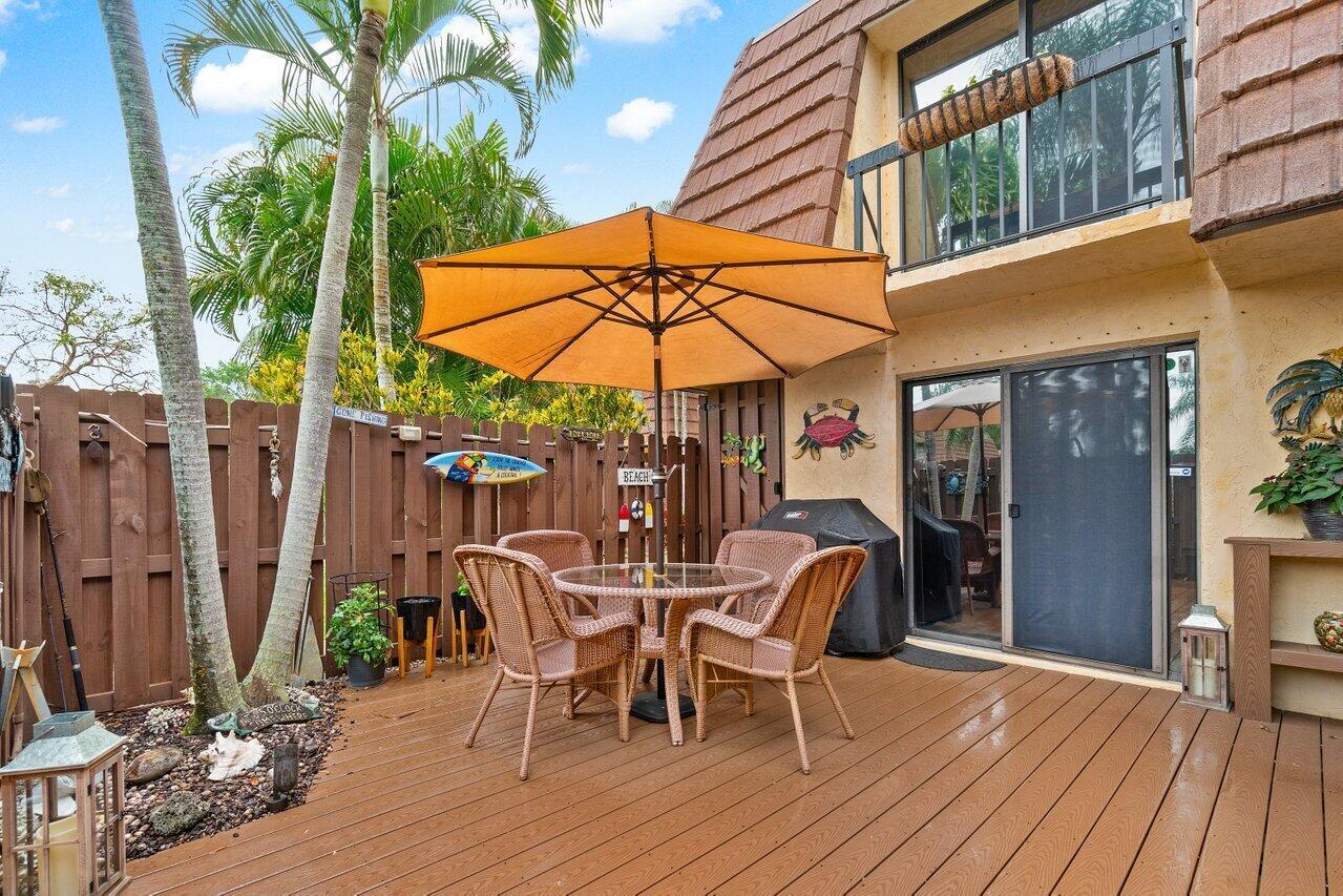 825 Center Street, Unit 13B Jupiter, FL 33458 - Photo 5 of 39 a view of a patio with a table and chairs under an umbrella with wooden floor