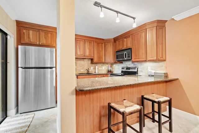 a kitchen with stainless steel appliances granite countertop a refrigerator and microwave