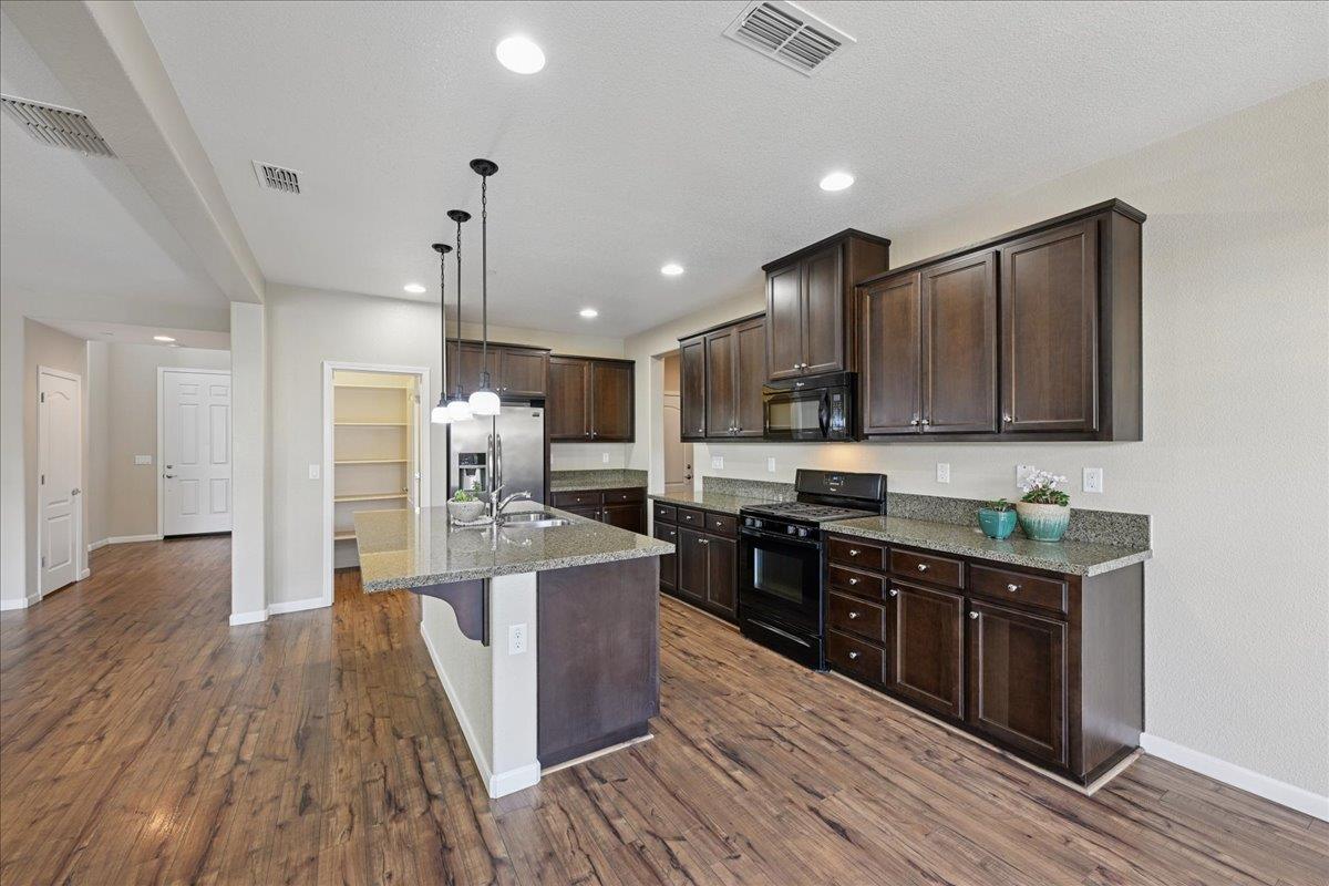 706 Wagon Trail Way Rocklin, CA 95765 - Photo 14 of 61 a large kitchen with stainless steel appliances wooden floors and wooden cabinets