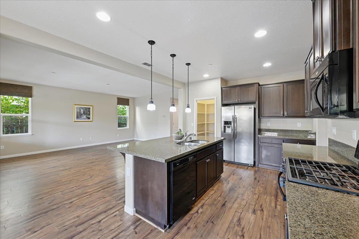 706 Wagon Trail Way Rocklin, CA 95765 - Photo 15 of 61 a kitchen with stainless steel appliances granite countertop a stove a refrigerator a sink dishwasher and a oven with wooden floor