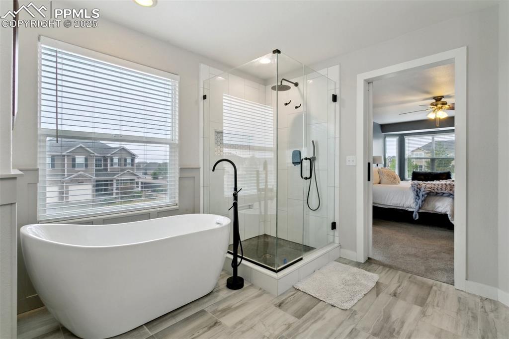 12912 Fishers Island Road Peyton, CO 80831 - Photo 19 of 45 a bathroom with a tub a window and a glass door shower