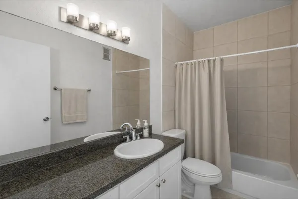 a bathroom with a granite countertop sink a toilet and a mirror