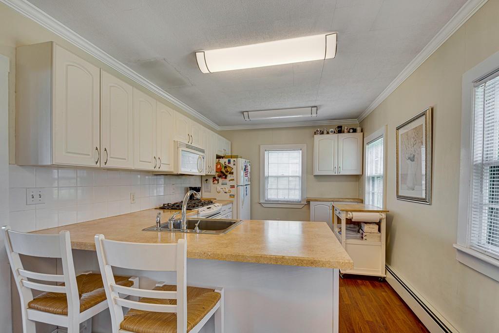 15 Greycliff Road Brighton, MA 02135 - Photo 4 of 41 a kitchen with granite countertop a stove a sink and white cabinets with wooden floors