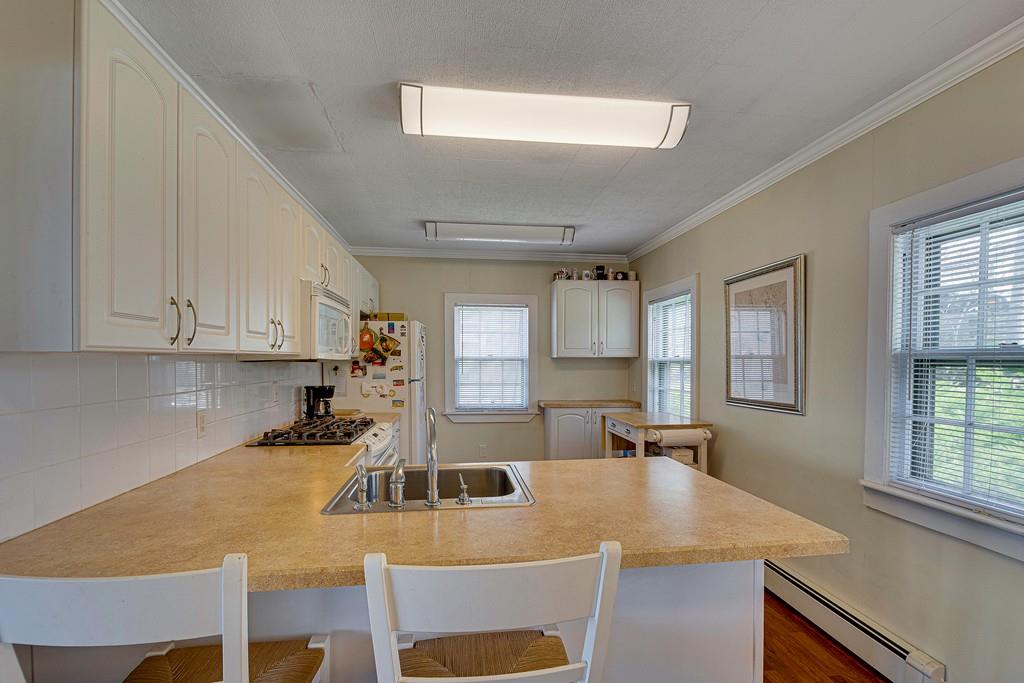 15 Greycliff Road Brighton, MA 02135 - Photo 5 of 41 a kitchen with kitchen island a stove a sink a refrigerator and white cabinets with wooden floor