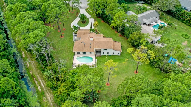 an aerial view of residential house with outdoor space and trees all around