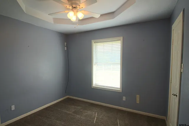 an empty room with a window and a fan