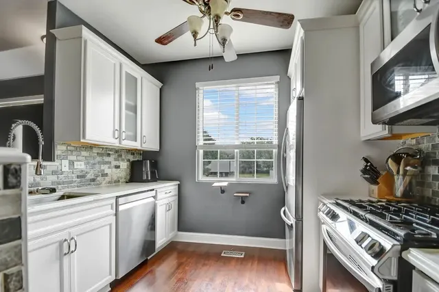 a kitchen with a stove a sink and wooden floor
