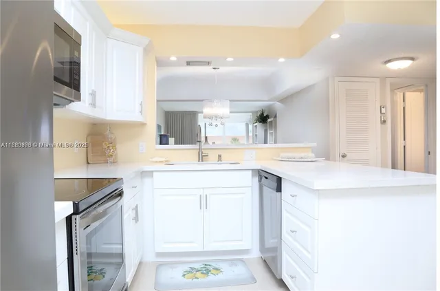 a kitchen with a sink dishwasher a stove a refrigerator with white cabinets and wooden floor