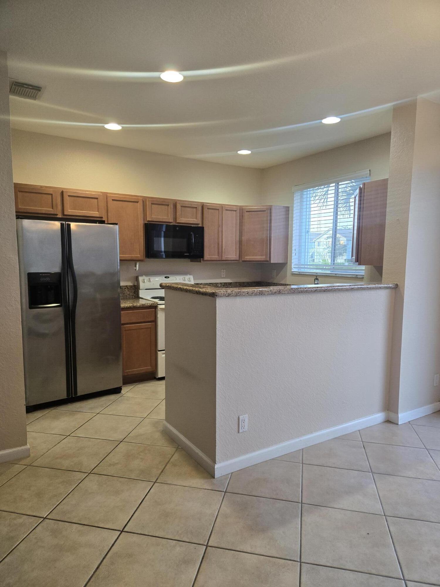 3182 Laurel Ridge Circle Riviera Beach, FL 33404 - Photo 13 of 29 a kitchen with stainless steel appliances granite countertop a refrigerator sink and microwave