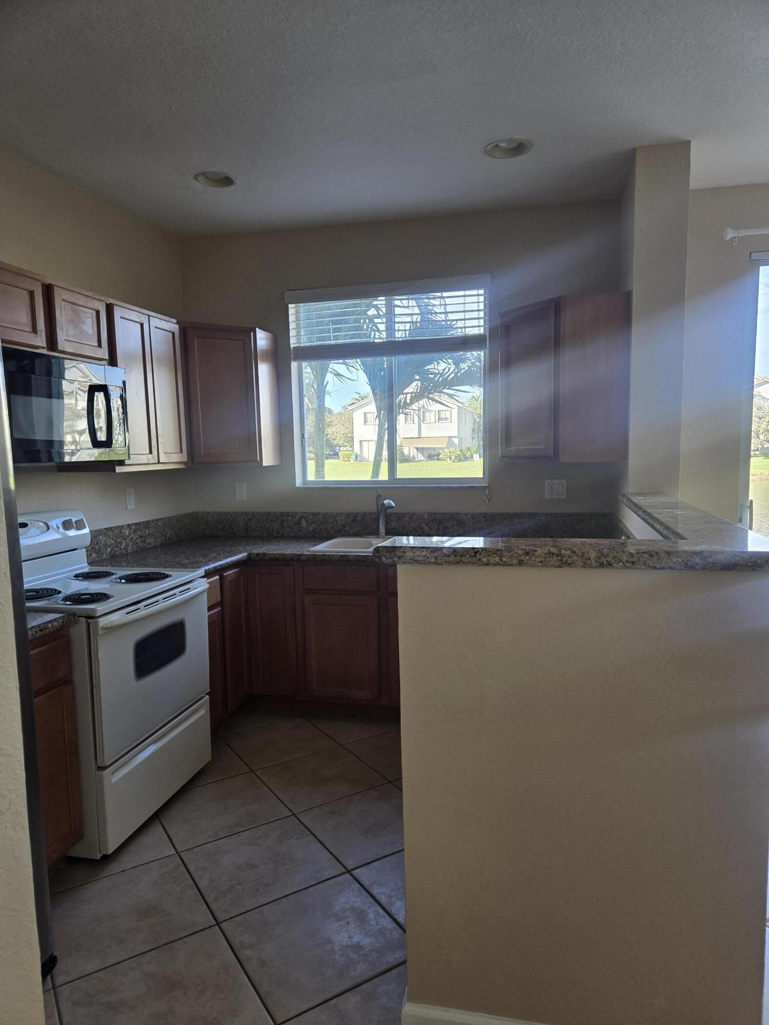 3182 Laurel Ridge Circle Riviera Beach, FL 33404 - Photo 17 of 29 a kitchen with granite countertop a stove and a sink