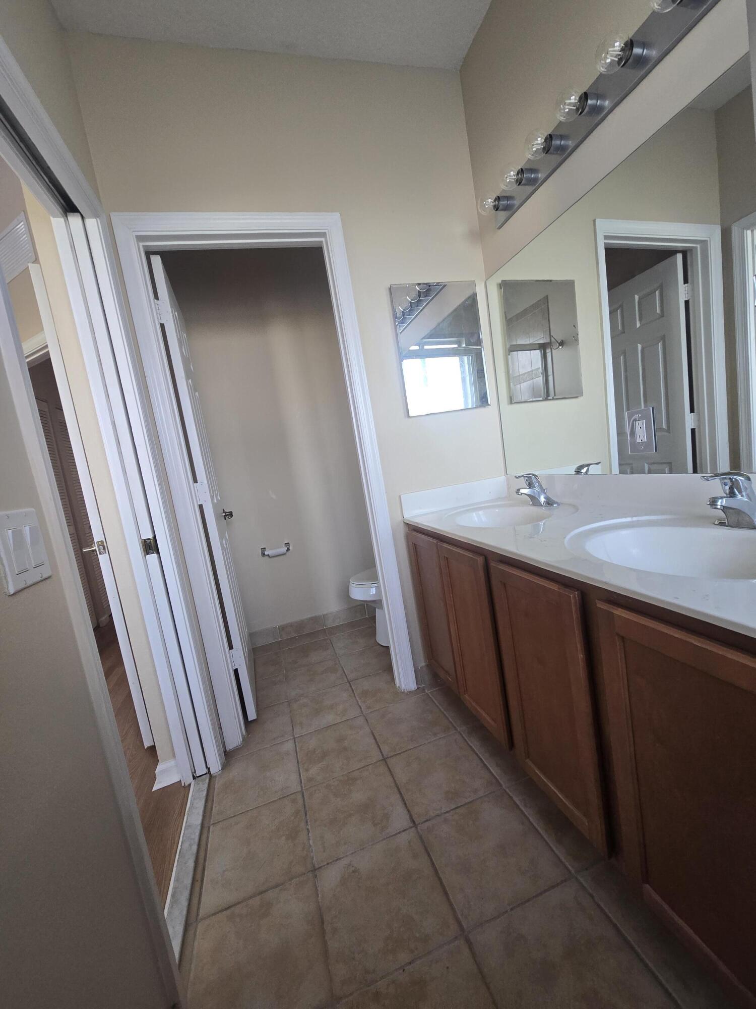 3182 Laurel Ridge Circle Riviera Beach, FL 33404 - Photo 29 of 29 a bathroom with a sink a toilet and mirror